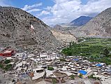 101 Marpha View Towards North After lunch in Jomsom, it took us only an hour to trek along the river bank much of the way to Marpha. Marpha (2680m) is situated in a little in a side valley and is protected from the strong winds, which blow in the middle of the river valley. The rooftops are bordered by neat stacks of firewood and provide a place where the women can work in the sun, drying and processing their produce. Everything in Marpha is clean and neat.